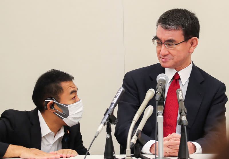 Japan's Vaccine Minister Taro Kono talks with his aide during a group interview in Tokyo