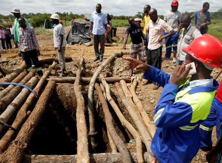 People gather over a shaft as retrieval efforts proceed for trapped illegal gold miners in Kadoma, Zimbabwe, February 15, 2019, REUTERS/Philimon Bulawayo