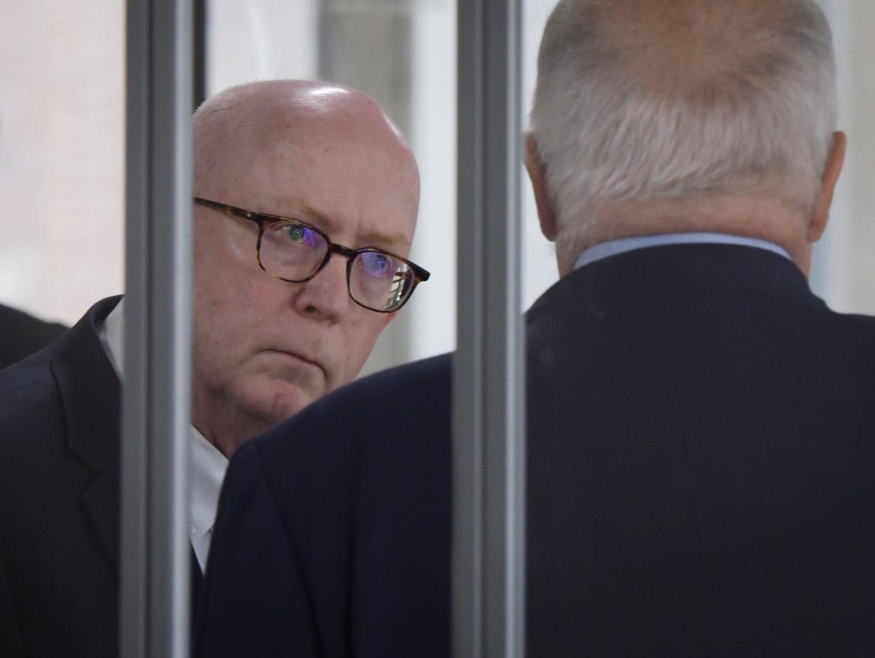 Prosecutor Jeffrey Travers talks with his lawyer Roy A. Bourgeois during a break in the Ethics Commission hearing on April 13, 2022.