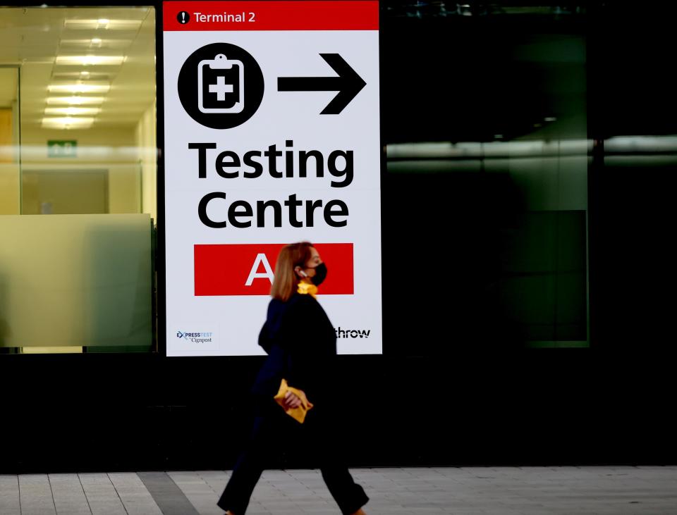 A passenger walks past a placard indicating the testing center in Heathrow Airport in London, Britain, Nov. 30, 2021. British Prime Minister Boris Johnson said Saturday all travellers entering Britain must take a PCR test by the end of the second day after their arrival, and must self-isolate until they receive a negative test result.   Passengers arriving in Britain from countries in Britain's travel 