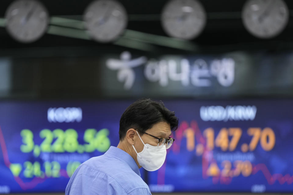 A currency trader walks by the screens showing the Korea Composite Stock Price Index (KOSPI), left, and the foreign exchange rate between U.S. dollar and South Korean won at the foreign exchange dealing room in Seoul, South Korea, Friday, July 9, 2021. Shares were mostly lower in Asia on Friday after stocks pulled back from their recent record highs on Wall Street as bond yields fell and investors turned cautious. (AP Photo/Lee Jin-man)