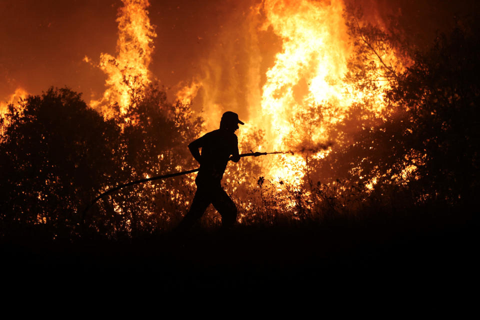 A firefighter tries to extinguish a wildfire burning at the industrial zone of the city of Volos, in central Greece, July 26, 2023. REUTERS/Alexandros Avramidis