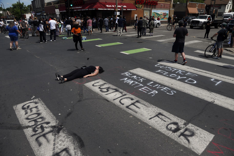 A woman lies in the street as protesters gather Wednesday, May 27, 2020 near the site of the arrest of George Floyd who died in police custody Monday in Minneapolis after video shared online by a bystander showed a white officer kneeling on his neck during his arrest as he pleaded that he couldn't breathe. (AP Photo/Jim Mone)