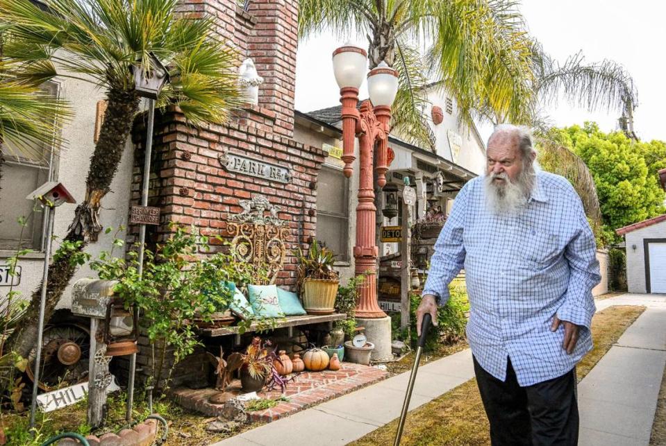 Jim Williams walks alongside his home decorated with old street lights, signs and historical artifacts in the Fresno High area where he has lived for 47 years. CRAIG KOHLRUSS/ckohlruss@fresnobee.com