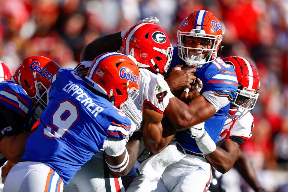 Oct 30, 2021; Jacksonville, Florida, USA;  Florida Gators quarterback Anthony Richardson (15) is tackled by Georgia Bulldogs linebacker Nolan Smith (4) in the first half at TIAA Bank Field. Nathan Ray Seebeck-USA TODAY Sports