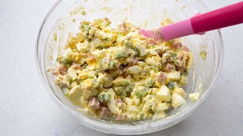 stirring egg salad in bowl