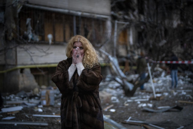 Natali Sevriukova stands near her house after a rocket attack in Kyiv, Ukraine, Friday, Feb. 25, 2022. (AP Photo/Emilio Morenatti)