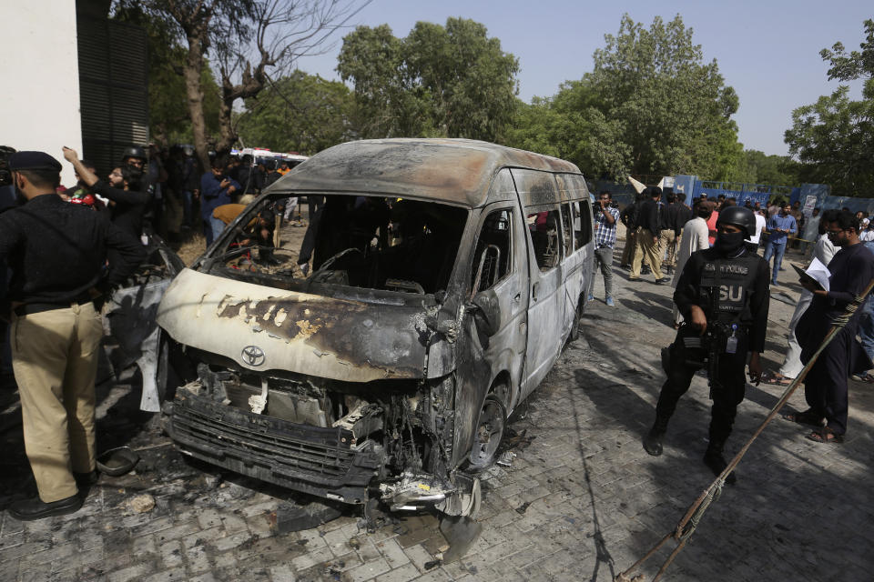 Pakistani investigators examine a burned van at the site of explosion in Karachi, Pakistan, Tuesday, April 26, 2022. The explosion ripped through a van inside a university campus in southern Pakistan on Tuesday, killing several people including Chinese nationals and their Pakistani driver, officials said. (AP Photo/Fareed Khan)