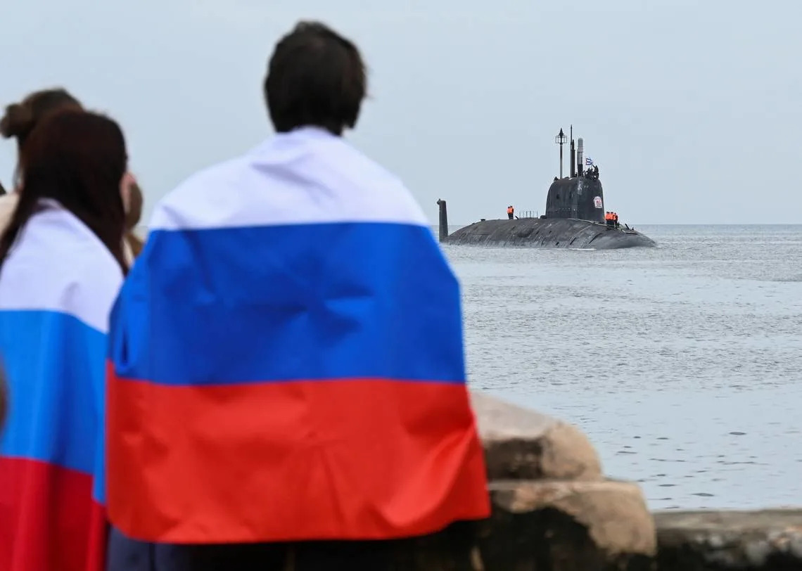 People wearing Russian flags watch as the Russian nuclear-powered submarine Kazan, part of the Russian naval detachment visiting Cuba, arrives at Havana Harbor on June 12, 2024. Photo by YAMIL LAGE / AFP) (Photo by YAMIL LAGE/AFP via Getty Images)