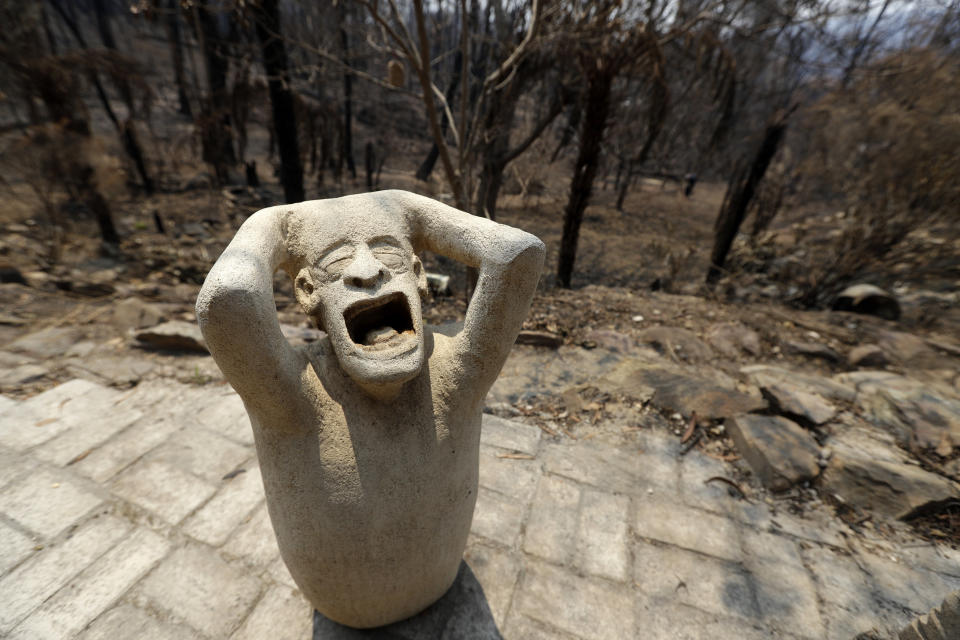 Sandstone sculptures by local fire captain Ron Threlfall show scenes of distress, Monday, Jan. 13, 2020, in Nerrigundah, Australia, that many residents of the town may have felt as a wildfire ripped through the town on New Year's Eve. The tiny village of Nerrigundah in New South Wales has been among the hardest hit by Australia's devastating wildfires, with about two thirds of the homes destroyed and a 71-year-old man killed. (AP Photo/Rick Rycroft)