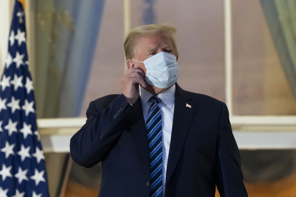 FILE - In this Oct. 5, 2020, file photo, President Donald Trump removes his mask as he stands on the Blue Room Balcony upon returning to the White House in Washington, after leaving Walter Reed National Military Medical Center, in Bethesda, Md. Trump announced he tested positive for COVID-19 on Oct. 2. (AP Photo/Alex Brandon, File)