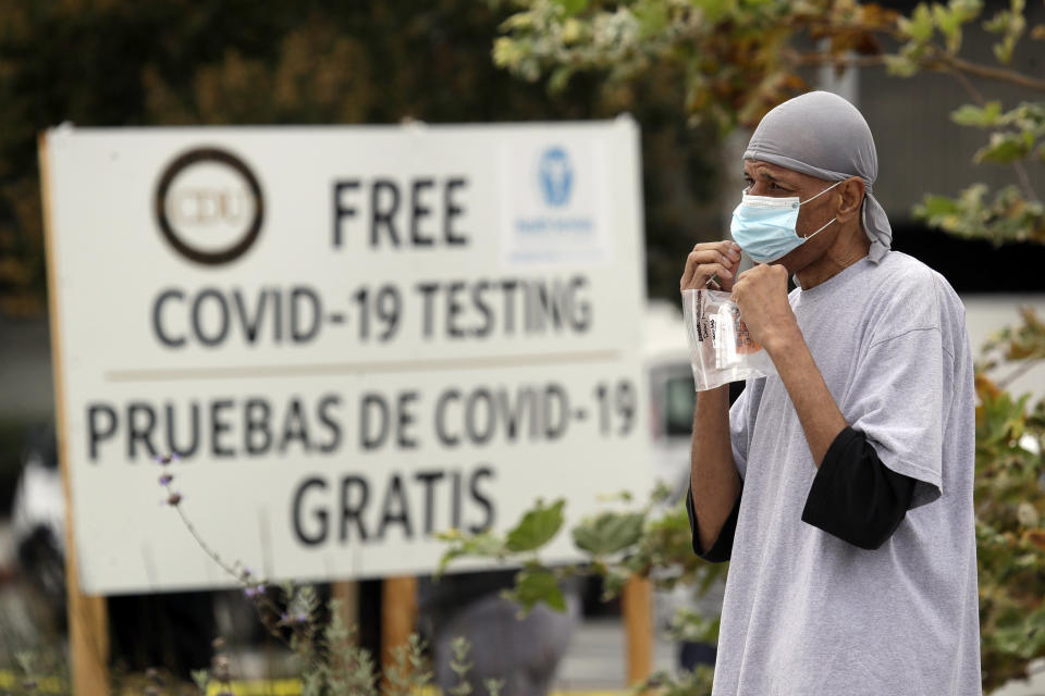 FILE - In this July 22, 2020, file photo, a man takes a coronavirus test at a mobile site at the Charles Drew University of Medicine and Science, in Los Angeles. California has stopped updating a list of counties facing more restrictions on businesses and schools after a problem in the state's coronavirus testing database has led to an undercount. (AP Photo/Marcio Jose Sanchez, File)