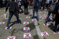 Anti-coup protesters walk on a road with defaced images of Commander in chief, Senior Gen. Min Aung Hlaing, in Yangon, Myanmar Thursday, March 4, 2021. Demonstrators in Myanmar protesting last month's military coup returned to the streets Thursday, undaunted by the killing of scores of people the previous day by security forces. (AP Photo)