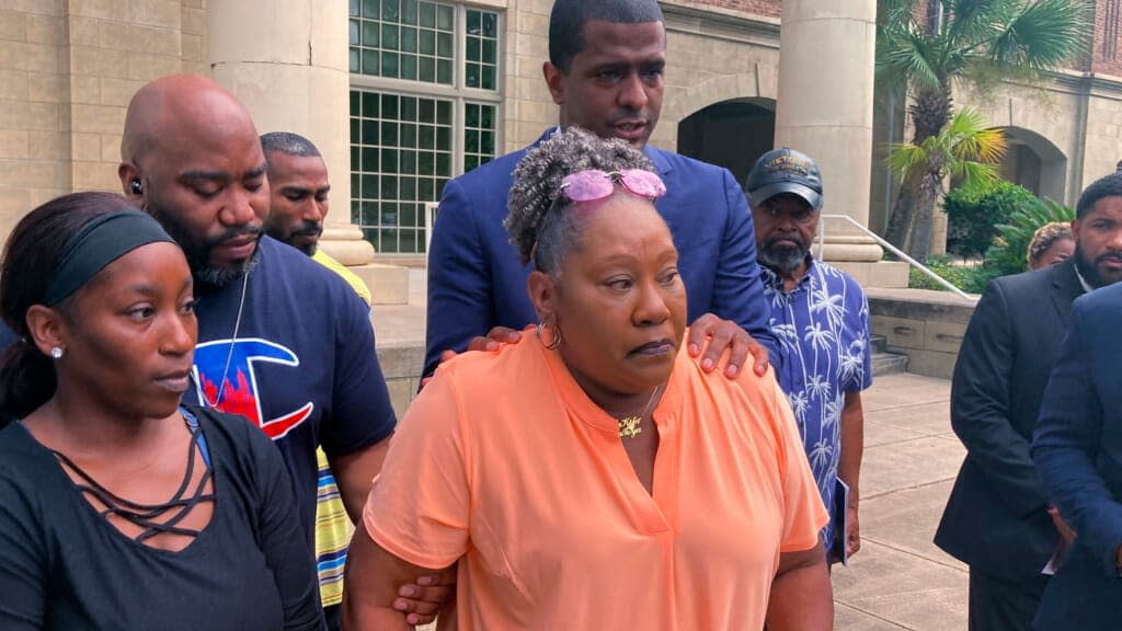 Betty James, center, is comforted by one of her attorneys, Bakari Sellers (standing behind her with hands on her shoulders) and family members during a news conference in Woodbine, Ga., on Monday, Aug. 22, 2022. (AP Photo/Russ Bynum)