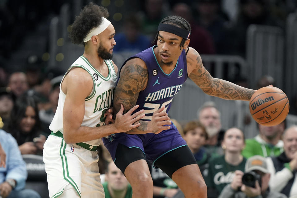 Boston Celtics guard Derrick White, left, defends as Charlotte Hornets forward P.J. Washington, right, drives toward the basket during the first half of an NBA basketball game, Monday, Nov. 28, 2022, in Boston. (AP Photo/Steven Senne)