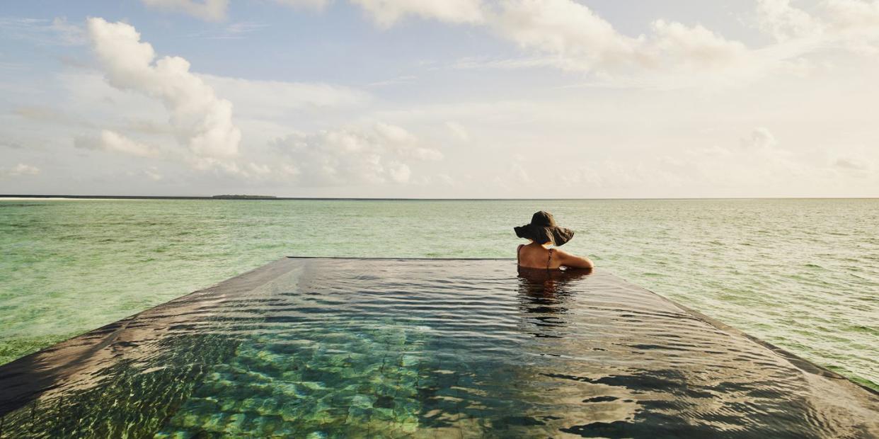 extreme wide shot of mature woman relaxing in infinity pool