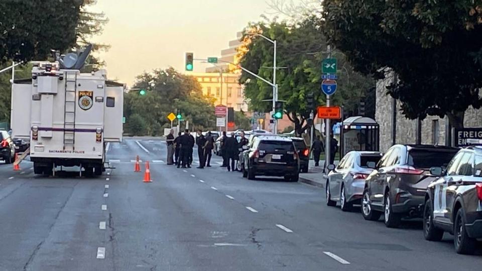 A mobile police unit and officers are seen at Fifth and L streets in downtown Sacramento following an officer-involved shooting that ended a standoff atop a parking garage Tuesday.