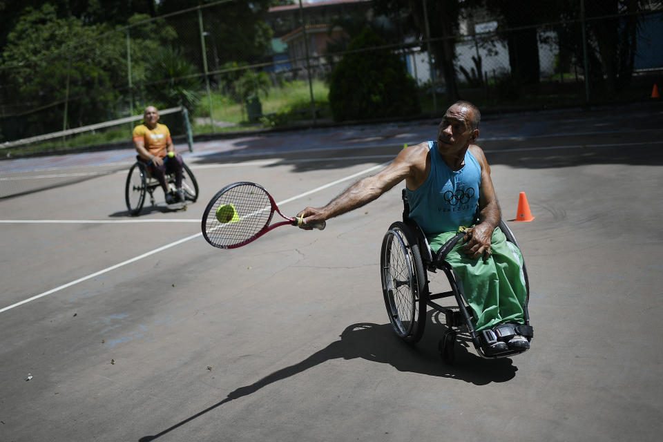 Manuel Mendoza juega tenis durante una sesión de entrenamiento con un amigo en silla de ruedas en el centro de tenis La Paz en el barrio La Paz de Caracas, Venezuela, el sábado 24 de octubre de 2020. (AP Foto/Matias Delacroix)