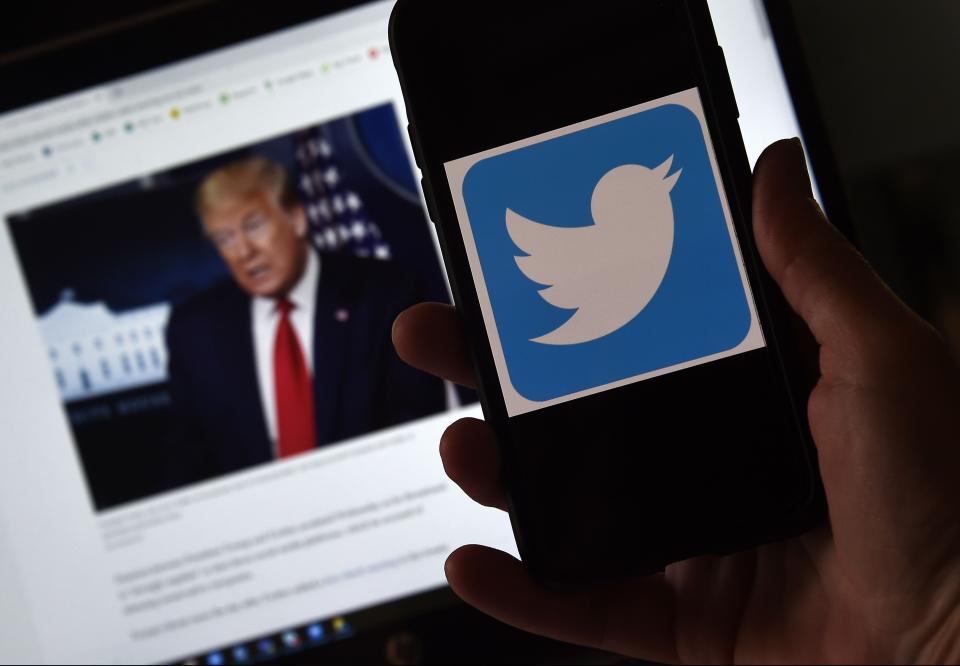 A Twitter logo is displayed on a mobile phone next to a picture of President Trump.