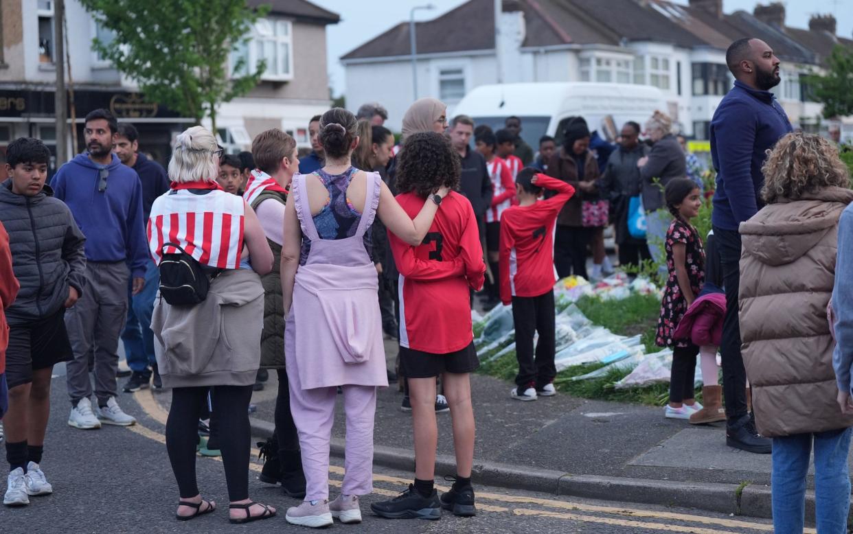 Crowds gather in the aftermath of the Hainault attack