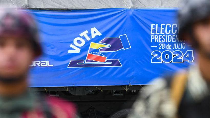 Militares delante de un cartel electoral promoviendo el voto en Venezuela. 