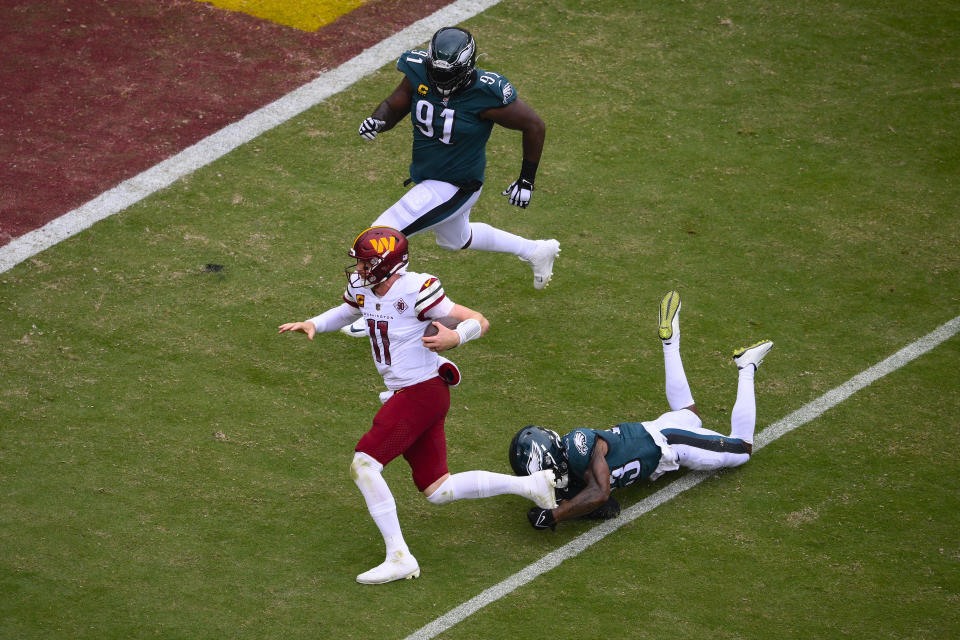 Washington Commanders quarterback Carson Wentz (11) scrambles with the ball against Philadelphia Eagles safety C.J. Gardner-Johnson (23) and Philadelphia Eagles defensive tackle Fletcher Cox (91) during the second half of an NFL football game, Sunday, Sept. 25, 2022, in Landover, Md. (AP Photo/Nick Wass)