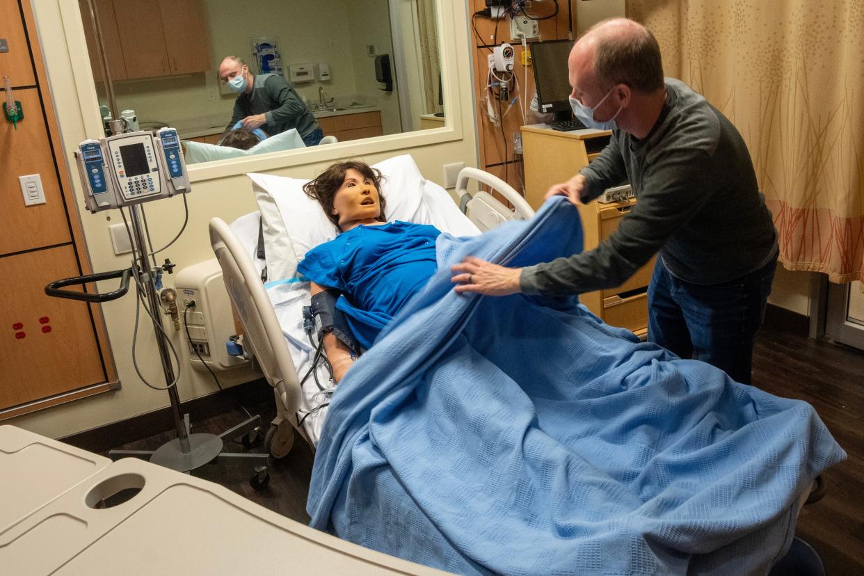 Simulation operations specialist David Delwiche covers up a mannequin in the nursing simulation lab at Marquette University.