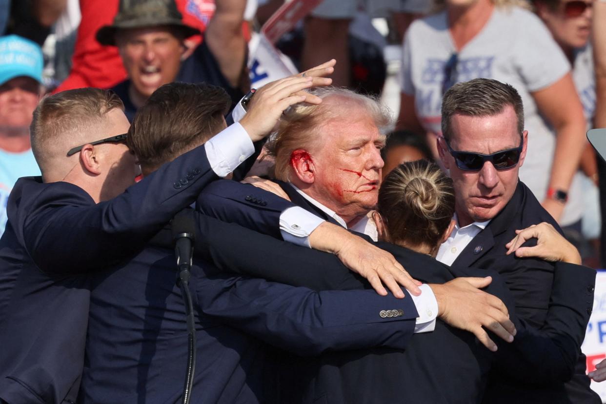 Republican presidential candidate and former U.S. President Donald Trump gestures with a bloodied face as multiple shots rang out during a campaign rally at the Butler Farm Show in Butler, Pennsylvania, on July 13, 2024.