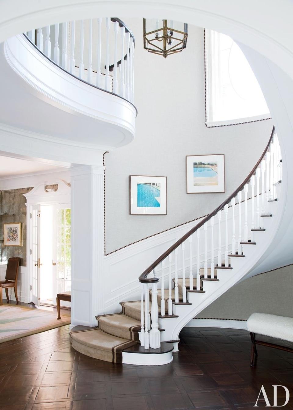 In the stately circular stair hall of a <a rel="nofollow noopener" href="https://www.architecturaldigest.com/story/steve-tisch-beverly-hills-home-article?mbid=synd_yahoo_rss" target="_blank" data-ylk="slk:Beverly Hills home;elm:context_link;itc:0;sec:content-canvas" class="link ">Beverly Hills home</a> decorated by Peter Dunham Design, the photographs are from Ed Ruscha's "Nine Swimming Pools" series; the walls are painted in Farrow & Ball's All White. <strong>Related:</strong> <a rel="nofollow noopener" href="https://www.architecturaldigest.com/decorating-with-color?mbid=synd_yahoo_rss" target="_blank" data-ylk="slk:AD’s Guide to Decorating with Color;elm:context_link;itc:0;sec:content-canvas" class="link "><em>AD</em>’s Guide to Decorating with Color</a>