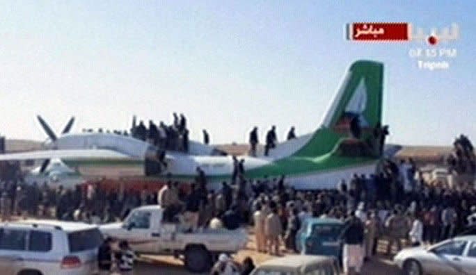 An image grab taken from the Libya Al-Ahrar TV station shows Libyan fighters climbing on the aircraft that brought Seif al-Islam, the fugitive son of ousted and killed Libyan leader Moamer Kadhafi, after it landed at an air strip in the town of Zintan, following Islam's arrest in southern Libya