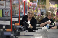 Cashiers at a grocery store sanitize a card reader and the checkout area, Thursday, March 26, 2020, in Quincy, Mass., as an extra precaution out of concern about the spread of the coronavirus. The new coronavirus causes mild or moderate symptoms for most people, but for some, especially older adults and people with existing health problems, it can cause more severe illness or death. (AP Photo/Steven Senne)