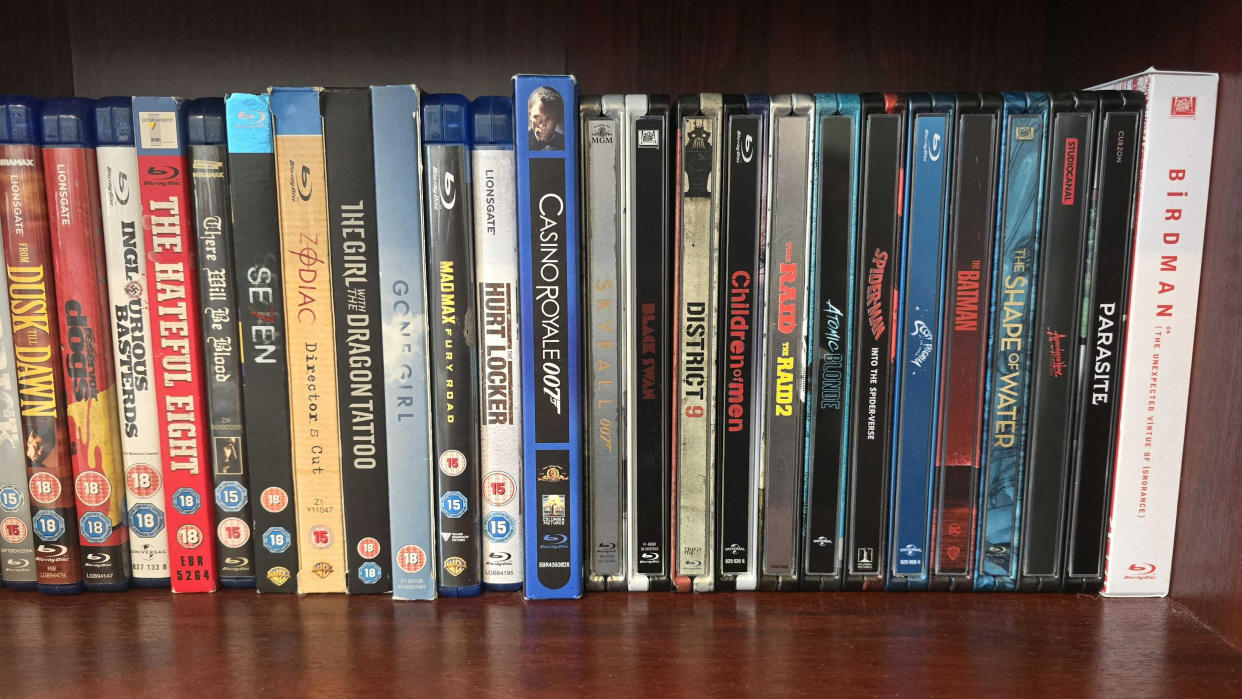  A stack of Blu-ray cases on a wooden shelf. 