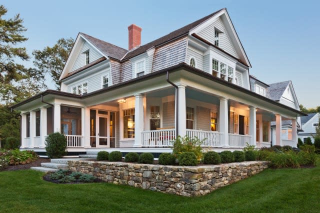 Exterior view of custom built home with exterior lighting and manicured landscaping.