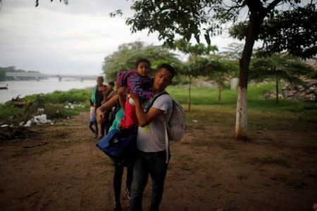 A central American migrant holds his daughter after crossing the Suchiate river on a raft from Tecun Uman, in Guatemala, to Ciudad Hidalgo, as seen from Ciudad Hidalgo