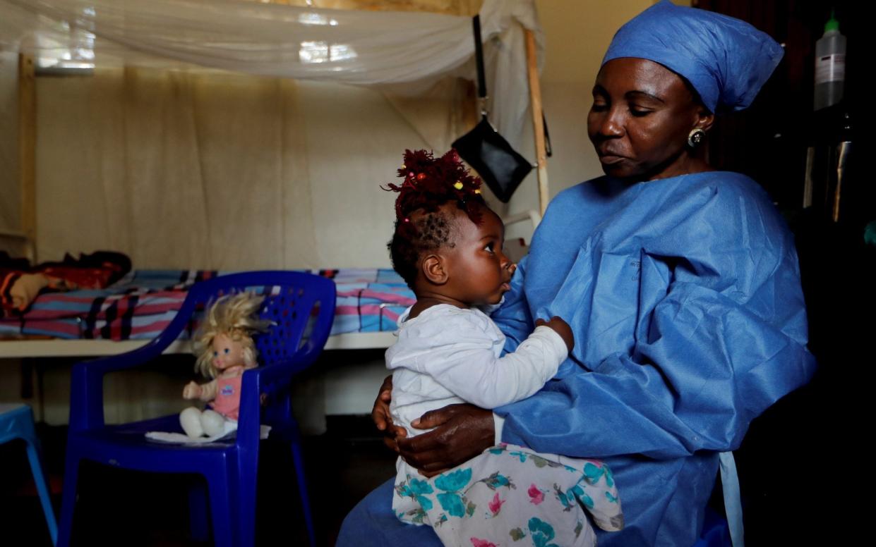 Kitambala Kavugho, 38, an Ebola survivor who works as a caregiver, takes care of one-year-old Chamim, an orphan whose mother recently died of Ebola - REUTERS