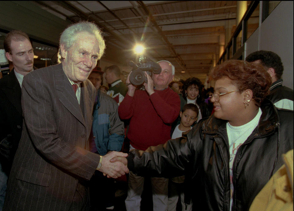 FILE - Aaron Feuerstein, left, president and owner of Malden Mills Industries Inc., in Methuen, Mass., shakes hands with workers on Jan. 11, 1996, in Lawrence, Mass. Feuerstein assured an extension of worker's wage and benefit packages after his employees were left jobless by a December 1995 fire that destroyed many buildings at his mill. Feuerstein died Thursday, Nov. 4, 2021. (AP Photo/Elise Amendola, File)