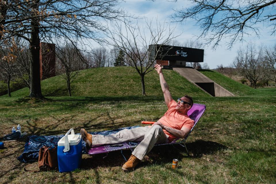 Justin Walker of Cuyahoga Falls waves at the sun and moon during a watch party for the 2024 solar eclipse at Trumpet in the Land Monday, in New Philadelphia. Walker said he came to New Philadelphia to get away from a lot of people.