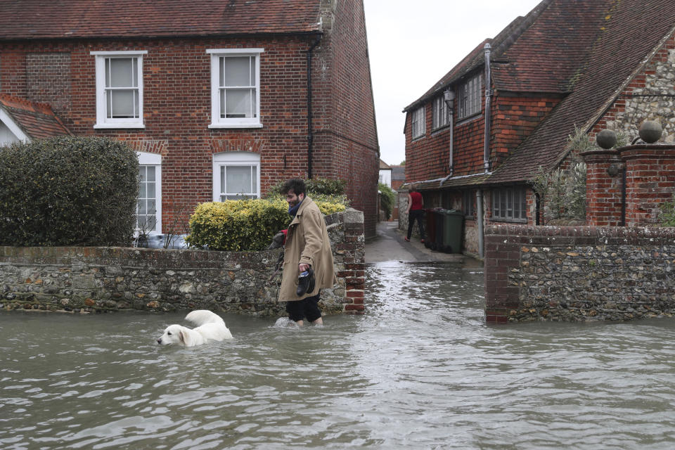 A man walks with a dog in flood water, in the aftermath of Storm Ciara, in Bosham, Sussex. (Steve Parsons/PA via AP)