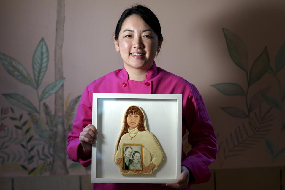 Artist Jasmine Cho holds a framed cookie portrait of the late Karen Fung Yee, in Pittsburgh, Pa., Wednesday, May 3, 2023. Cho, a Korean American self-described “cookie activist,” has gained fans over the last several years for her finely detailed portraits of famous and forgotten figures. Yee, a second generation Chinese American from Pittsburgh and educator of Asian culture, died in 2019. (AP Photo/Matt Freed)