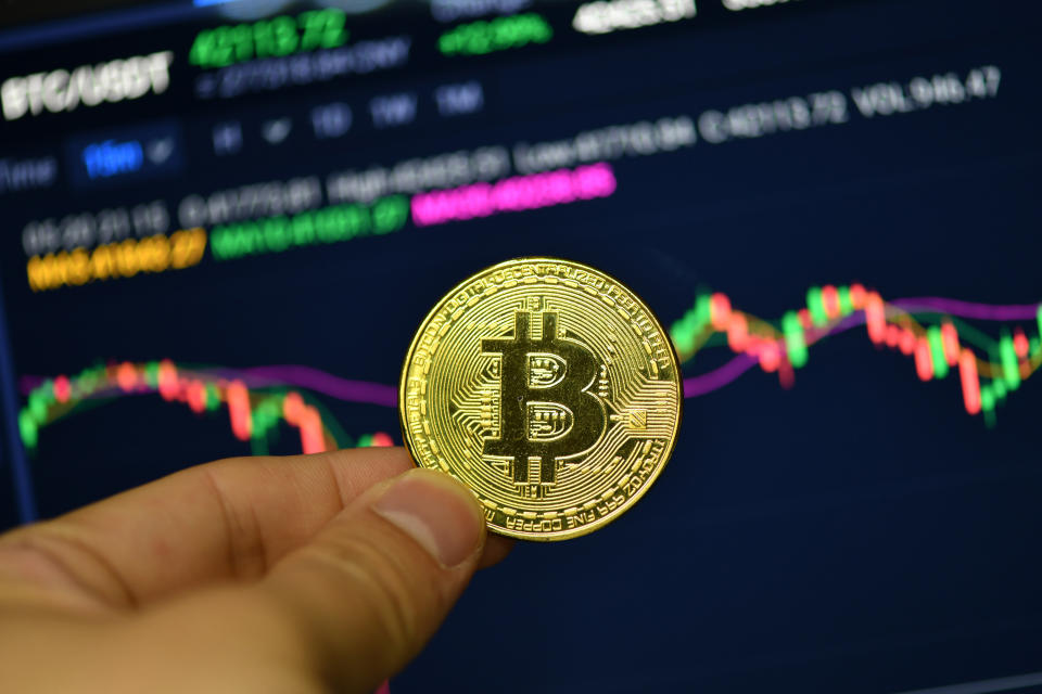 CHINA - 2021/05/20: In this photo illustration a Bitcoin is seen on display with a Bitcoin price trend chart in the background. (Photo Illustration by Sheldon Cooper/SOPA Images/LightRocket via Getty Images)