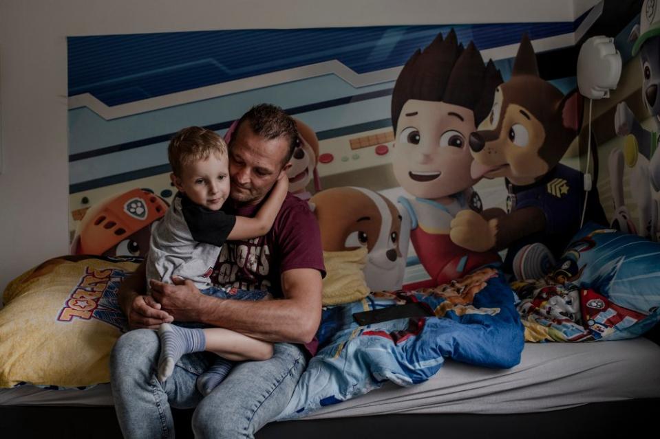 Janusz Kucharski holds his son Dawid in their home in Radoszowy, Poland, on July 30. They lost their partner and mother Justyna Szymura on Dec. 11, 2020. “I would never give him up, although I don't know any other father raising a child alone,” Janusz says <span class="copyright">Kasia Strek for TIME</span>