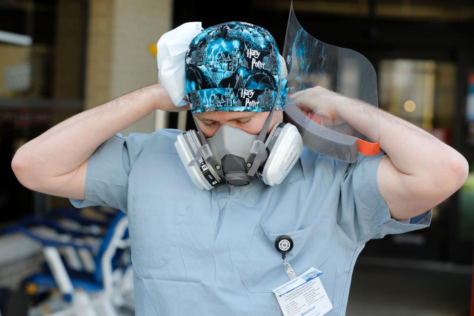 Canadian nurse Steve Homick is photographed  putting on his protective gear outside of the Emergency Entrance before the start of his shift at Beaumont Hospital in Royal Oak, Michigan on April 26, 2020. - The Canada-US border was ordered closed to all non-essential travel in March. Canadian healthcare workers, who are exempt from the travel restriction, are today at the forefront of the fight against the coronavirus in the United States where nearly 70,000 people have died from COVID-19, making it the most infected country in the world. (Photo by JEFF KOWALSKY / AFP) (Photo by JEFF KOWALSKY/AFP via Getty Images)