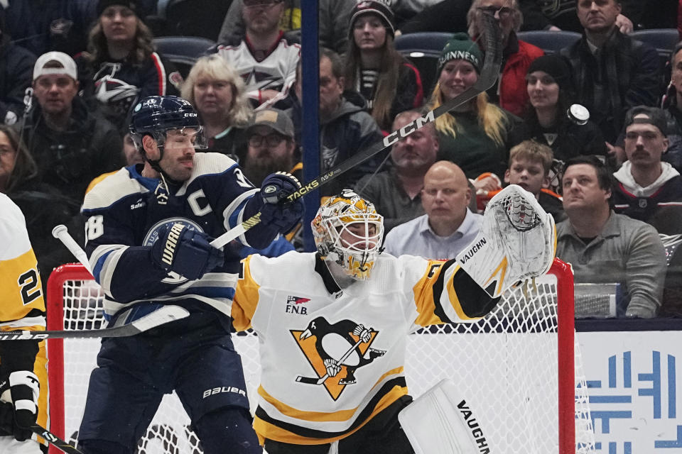 Pittsburgh Penguins goaltender Tristan Jarry, right, watches the puck, next to Columbus Blue Jackets center Boone Jenner (38) during the first period of an NHL hockey game Tuesday, Nov. 14, 2023, in Columbus, Ohio. (AP Photo/Sue Ogrocki)