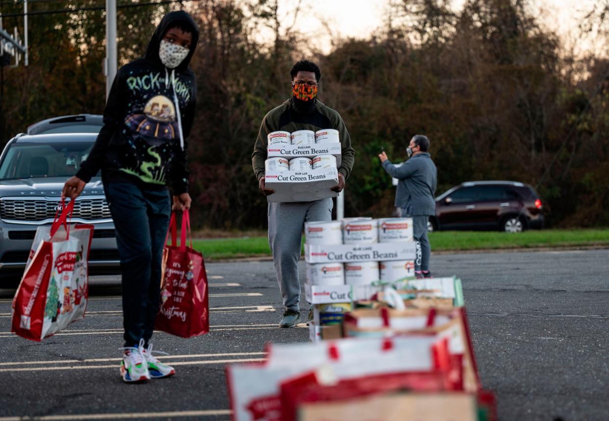 Volunteers carry food to be given to members of the community, sponsored by resident Linda Flowers, during a pre-Thanksgiving food handout in Fort Washington, Maryland on Nov. 20, 2020. Flowers, a survivor of Covid-19, holds a community food handout each Friday to honor her late father, Bishop James N. Flowers, who passed away from Covid-19 in April 2020.