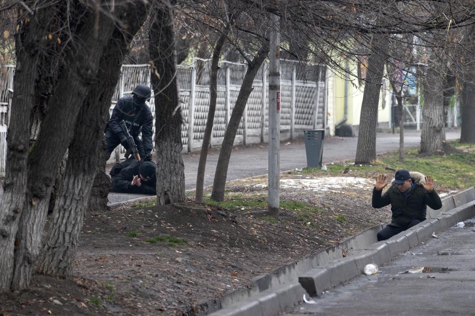 FILE - An armed riot police officer detains two protesters during a security anti-terrorists operation in a street after clashes in Almaty, Kazakhstan, Saturday, Jan. 8, 2022. The government, by then led by Nazarbayev's close ally Tokayev, responded with a deadly clampdown, culminating in a "shoot-to-kill" order as the president blamed "terrorists" allegedly funded and trained from abroad. (AP Photo/Vasily Krestyaninov, File)