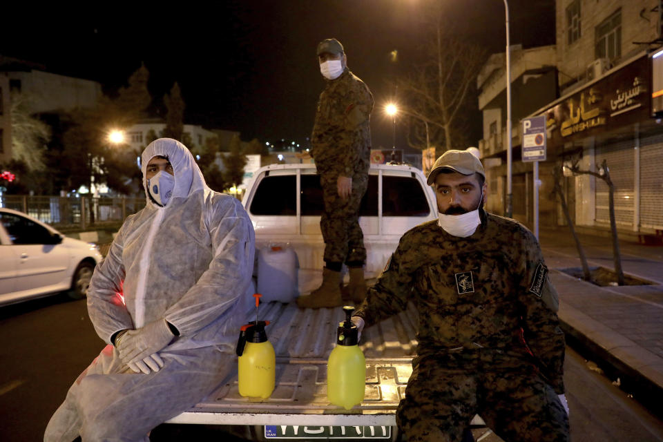 In this Wednesday, March 4, 2020, photo, Revolutionary Guard members take part in disinfecting the city to help prevent the spread of the new coronavirus in Tehran, Iran. Wearing gas masks and waterproof fatigues, members of Iran's Revolutionary Guard now spray down streets and hospitals with disinfectants as the Islamic Republic faces one of the world's worst outbreaks of the new coronavirus. (AP Photo/Ebrahim Noroozi)