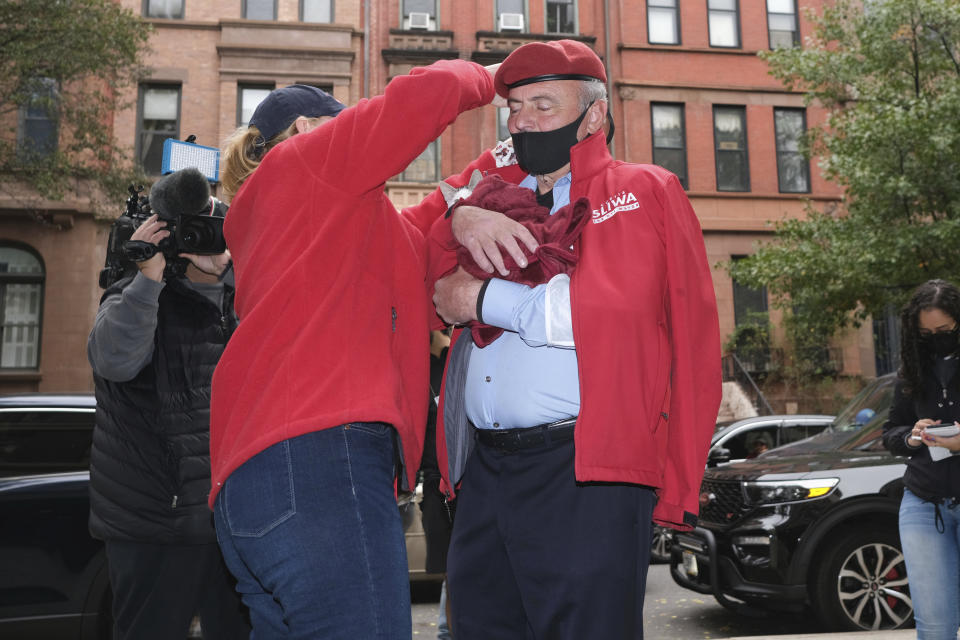 Mayoral candidate Curtis Sliwa's wife, Nancy Regula, helps Sliwa get his mask on while he holds a cat before entering a polling place in New York, Tuesday, Nov. 2, 2021. (AP Photo/Seth Wenig)