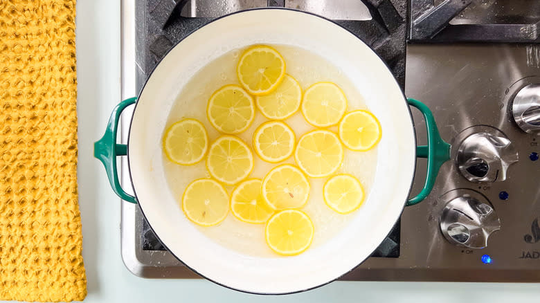 Lemon wheels cooking in sugar and water in saucepan on stovetop