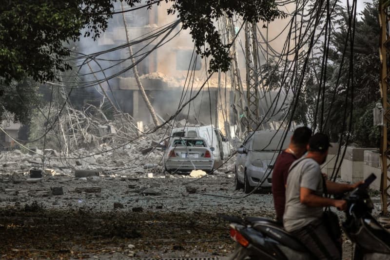 People inspect damages after Israeli air raids at a street in Beirut southern suburb. Stringer/dpa