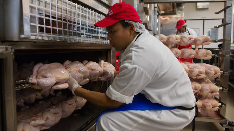 Deli worker putting chicken in rotisserie
